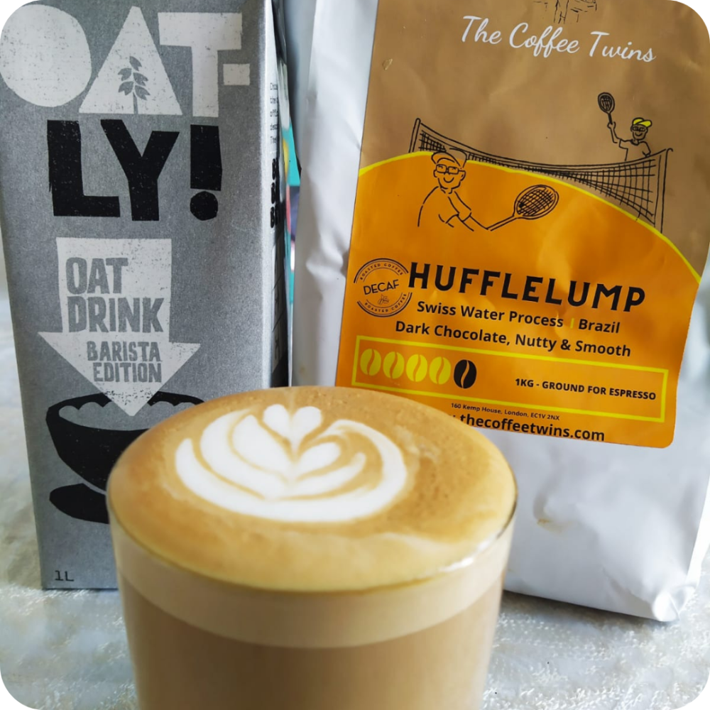 Oatly Milk carton with a bag of decaf Hufflelump coffee and a latte at the front of the photo