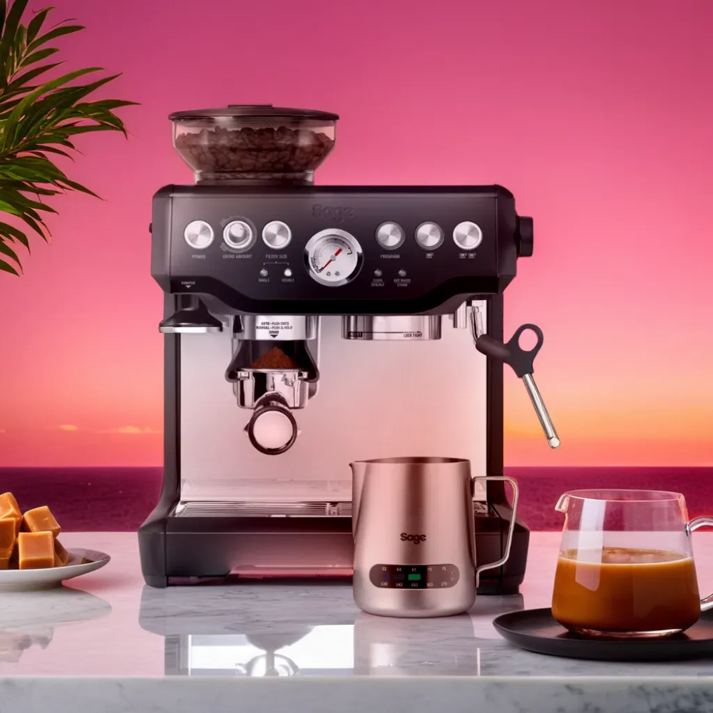 barista expresso machine with a plant, caramel sat on a marble kitchen top and a jug of coffee