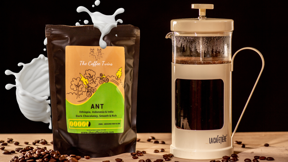 The Coffee Twins 'Ant' blend coffee bag with a cafetiere  with coffee inside with a splash of milk around the coffee bag