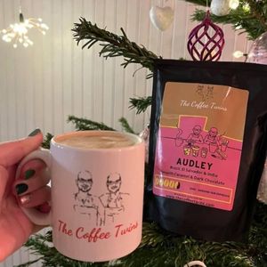 a lady holding a mug of coffee with the audley the coffee twins bag of coffee