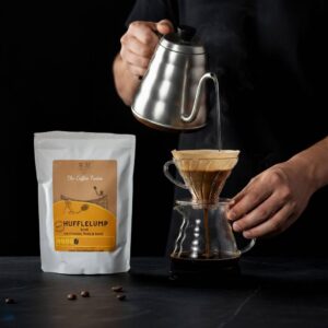 A person pouring hot water over coffee grounds in a filter with Hufflelump coffee bag from The Coffee Twins in view.