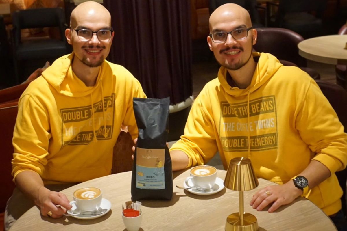 The Coffee Twins sitting at a café table with Bobo Medium Roast Coffee and two lattes