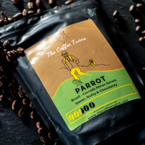 The Coffee Twins Parrot coffee, a Brazilian single-origin speciality coffee from Cerrado Minas Gerais, photographed in its black retail bag with roasted coffee beans. Known for sweet, nutty, and chocolatey flavour notes.