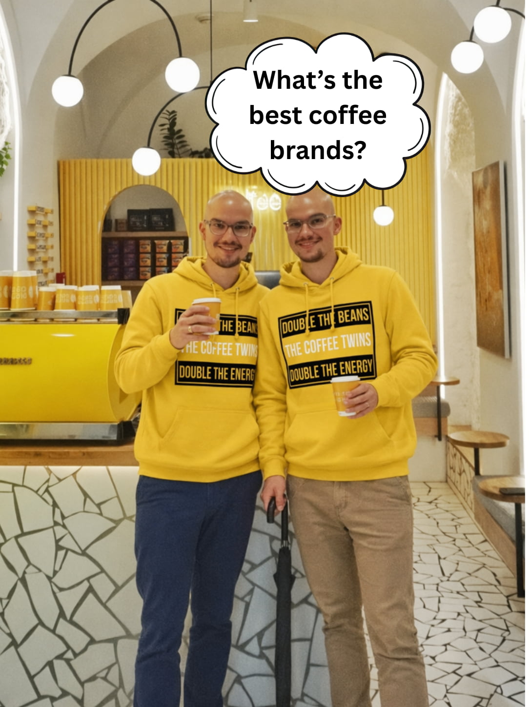 The Coffee Twins standing together in a bright yellow coffee shop, holding takeaway coffees beneath a thought bubble asking “What’s the best coffee brands?”