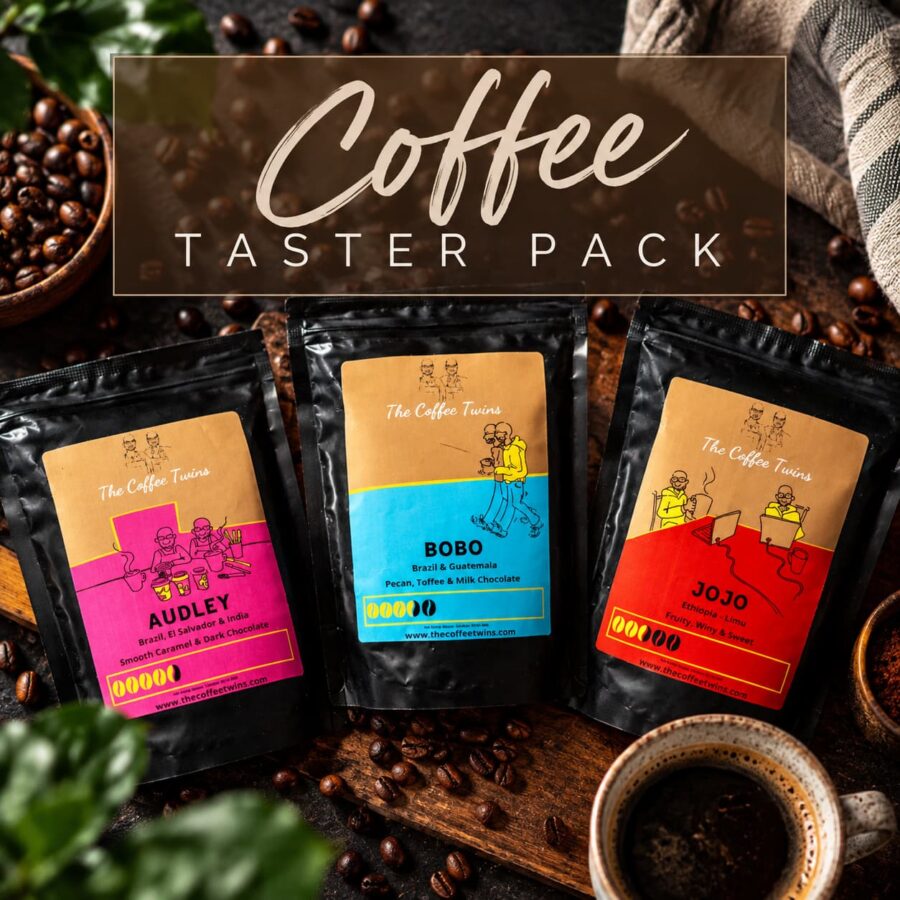 The Coffee Twins Coffee Taster Pack featuring Audley, Bobo and Jojo coffee bags displayed with coffee beans and freshly brewed coffee on a rustic wooden table.